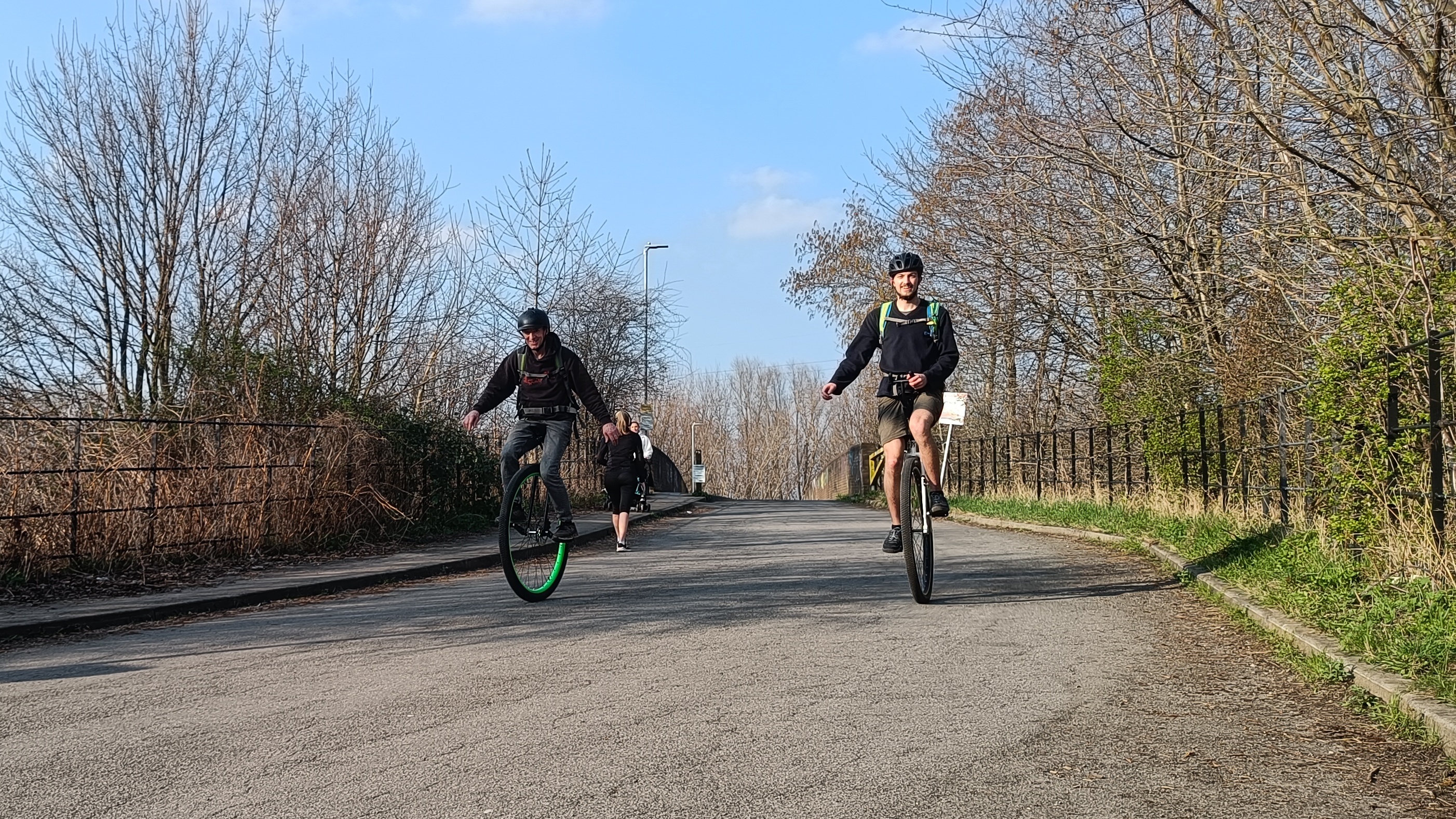 Two unicyclists riding on large wheels