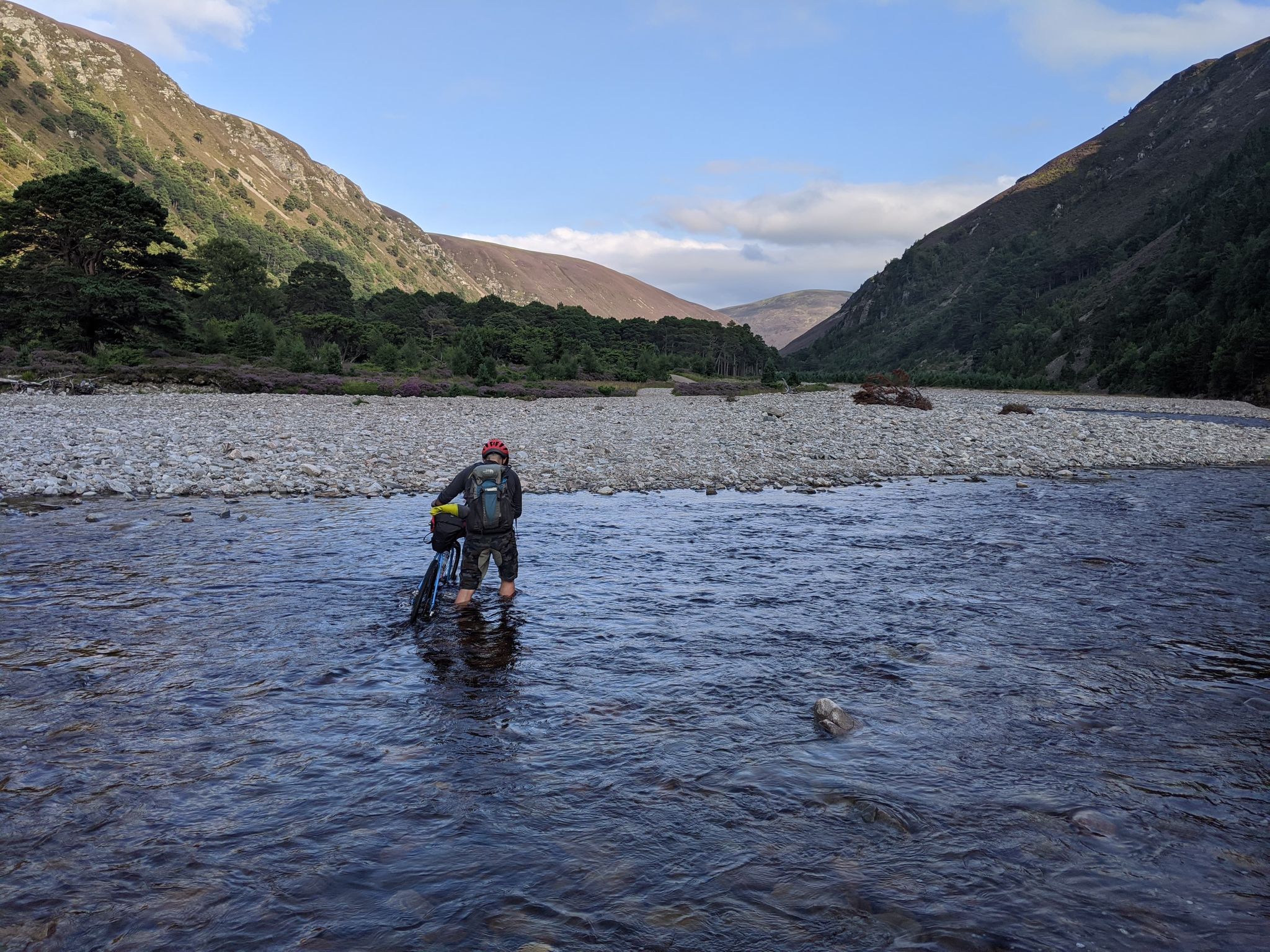 A cyclist wades across a river