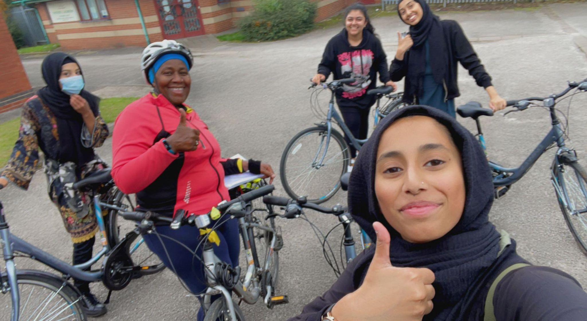 people standing smiling with their bikes on a cycle path