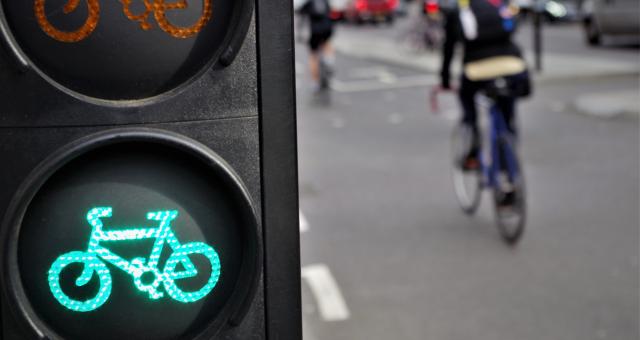 Cyclist going through green cycle lane light 