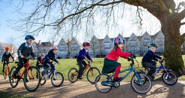 A group of school children cycle along a country park path together