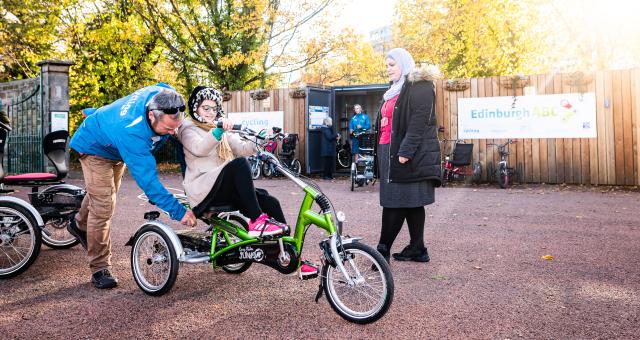 Instructor coaching someone on a tricycle