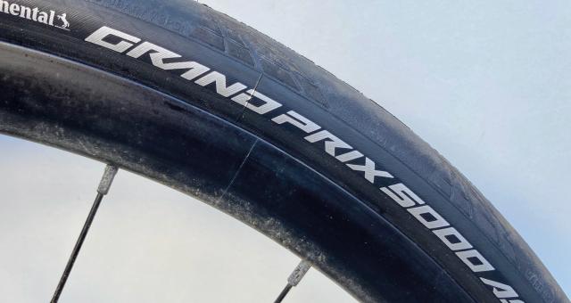 A close-up of a bike tyre showing the tyre model: Grand Prix 5000 AS