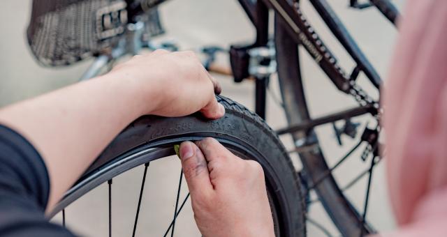 A cyclist prying off the tyre on her bike. 