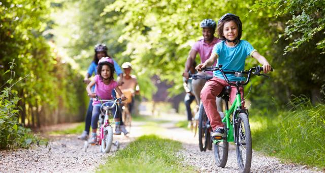 A family is riding on a trail through woods