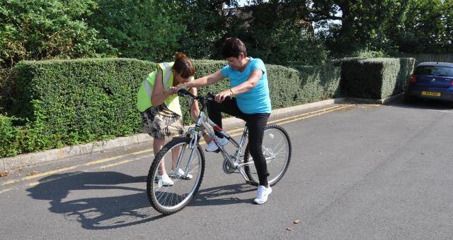 Julie teaching Alicia to ride a bike 