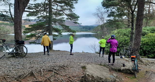 group of cyclists taking a break at a loch