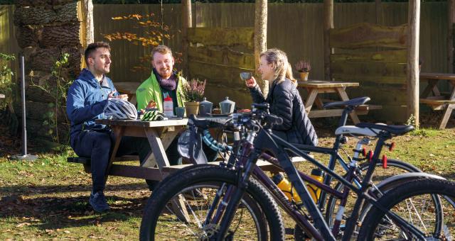 Three cyclists at an outdoor cafe discussing cycling  