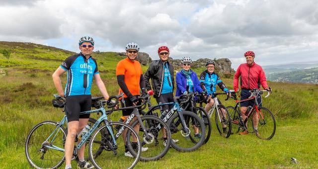 A group of cyclists with their bikes stand on a green hill