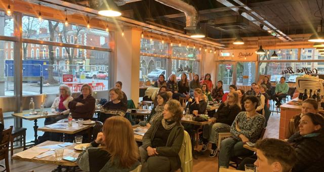 A large group of women sit at small tables in a busy cafe