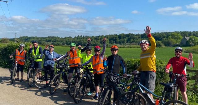 A group of cyclists waving at the camera