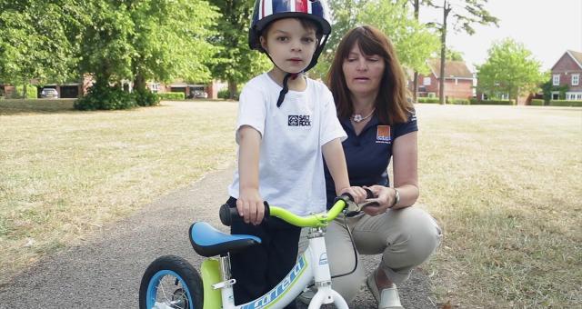 A child being taught how to ride a balance bike. 