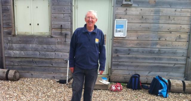 A man is standing in front of a shed